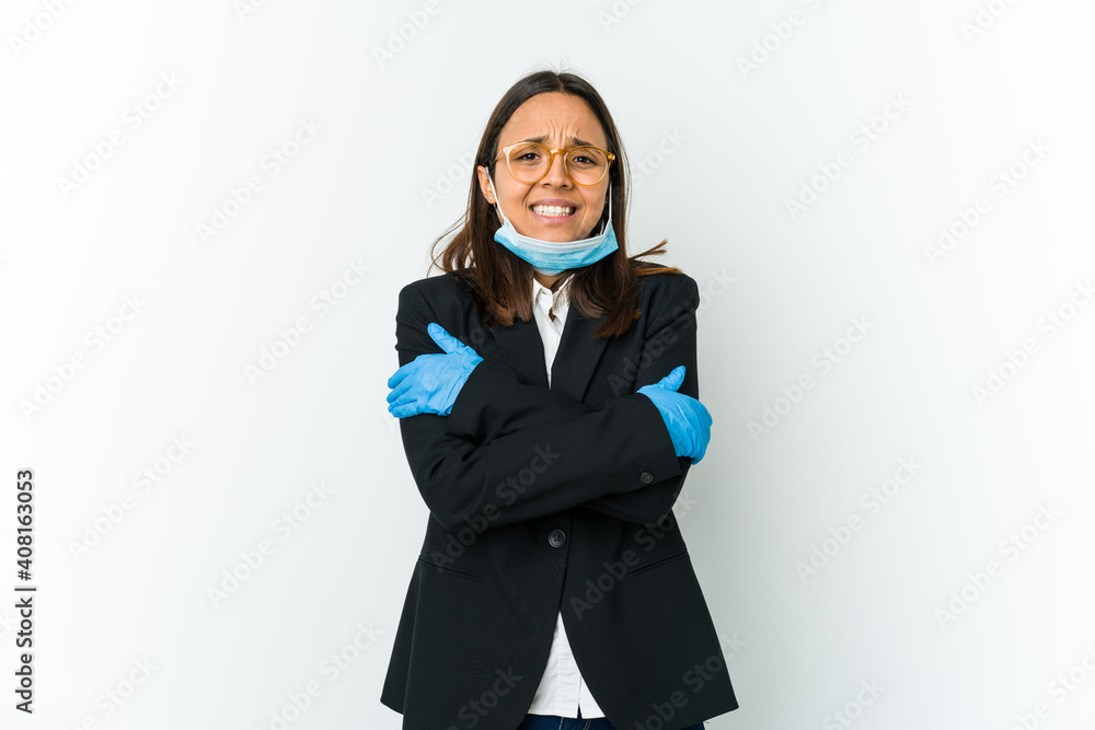 Young business latin woman wearing a mask to protect from covid isolated on white background going cold due to low temperature or a sickness. Young business latin woman wearing a mask to protect from covid isolated on white background going cold due to low temperature or a sickness.