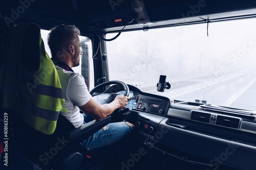 Handsome driver at the wheel of a truck at work. Work of a lorry driver. photo