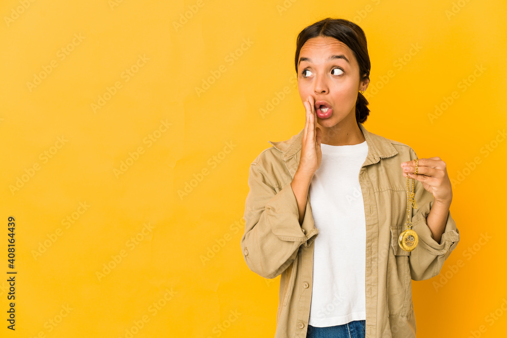 Young hispanic woman holding a pocket watch is saying a secret hot braking news and looking aside Young hispanic woman holding a pocket watch is saying a secret hot braking news and looking aside