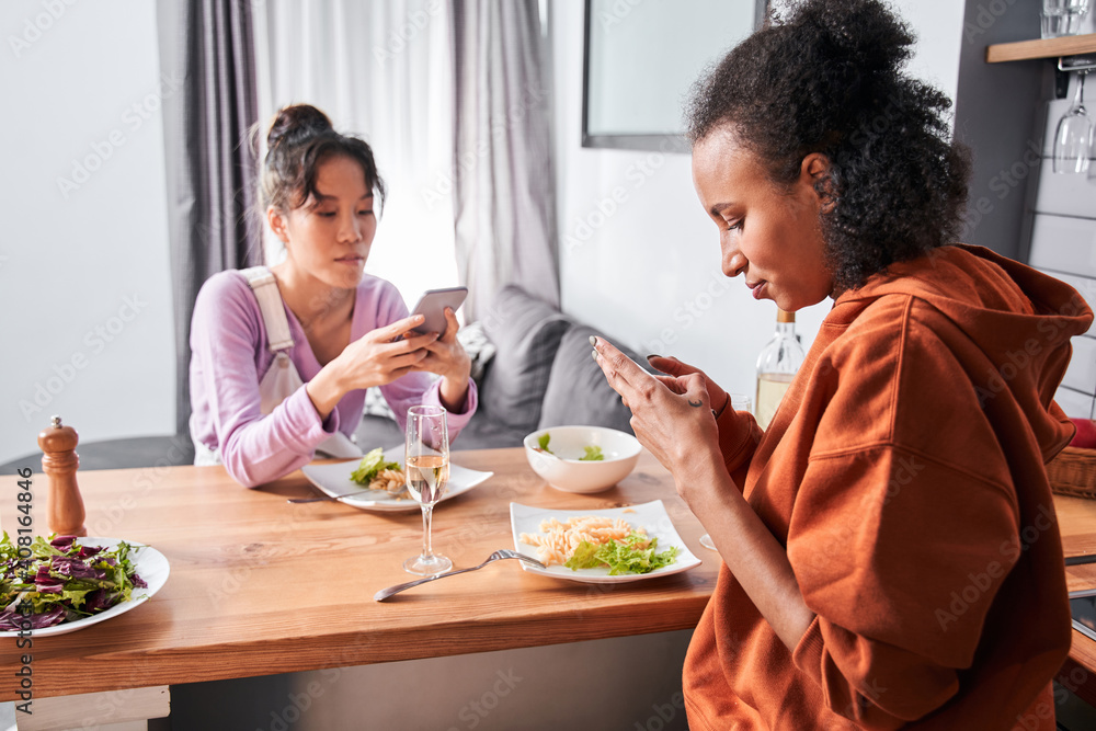 Girls using smartphones while having dinner Girls using smartphones while having dinner