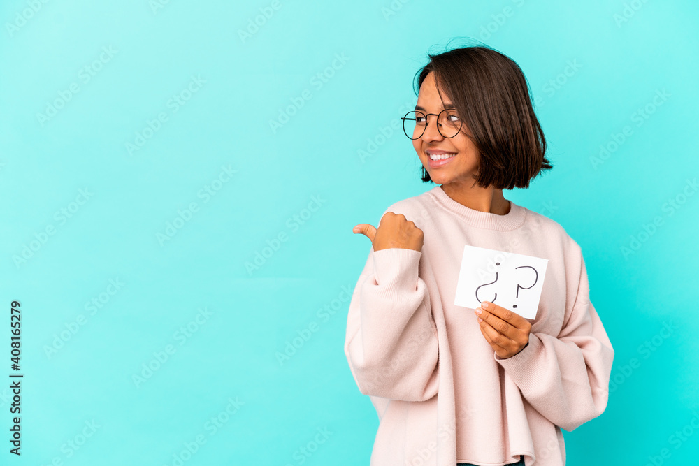 Young hispanic mixed race woman holding an interrogation board points with thumb finger away, laughing and carefree. Young hispanic mixed race woman holding an interrogation board points with thumb finger away, laughing and carefree.