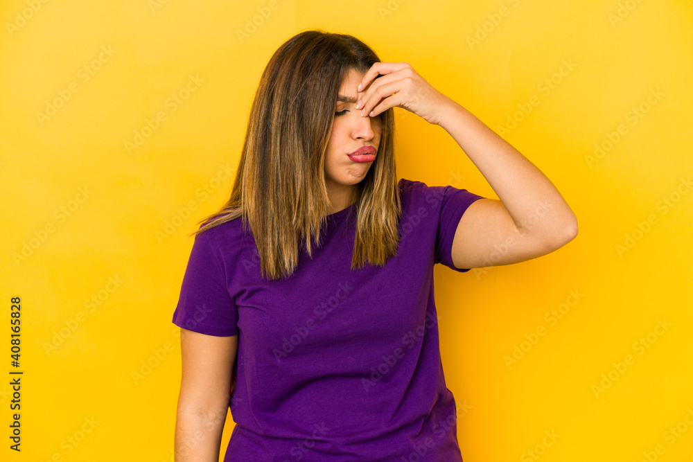 Young indian woman isolated on yellow background having a head ache, touching front of the face. Young indian woman isolated on yellow background having a head ache, touching front of the face.