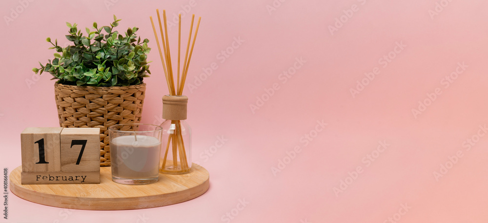 calendar. 17 february composition from a wooden calendar, a flower in a wicker pot, a gray candle in a glass candlestick and an aroma diffuser on a light pink background banner business calendar. 17 february composition from a wooden calendar, a flower in a wicker pot, a gray candle in a glass candlestick and an aroma diffuser on a light pink background banner business