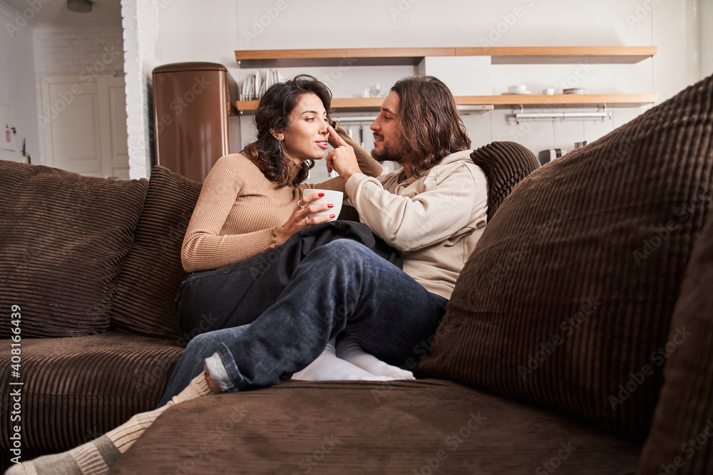 Couple in love enjoying their free time while sitting at sofa