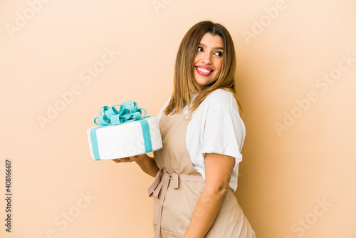 Young indian pastry chef woman isolated looks aside smiling, cheerful and pleasant. © Asier