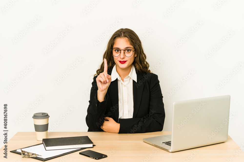 Young caucasian business woman working on her desktop isolated showing number one with finger. Young caucasian business woman working on her desktop isolated showing number one with finger.