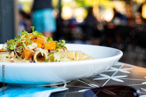 White plate with a pasta, chicken and roasted butternut meal