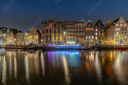illuminated boat with city at night in Amsterdam.