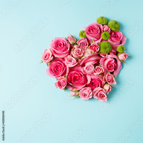 Heart shaped bouquet of beautiful fresh pink rose flowers on pastel blue background. Minimal Valentines Day, Easter, wedding or Mother's day concept. Creative spring or summer floral layout. Flat lay.