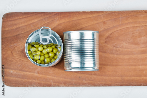 Two cans of boiled green peas on a wooden board photo