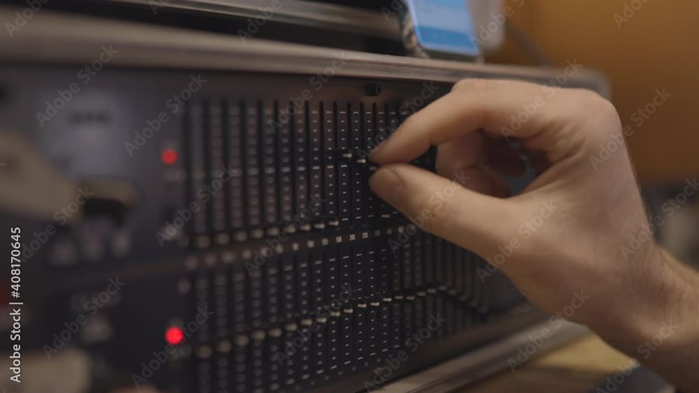 Hand works on graph equalizer display in the studio. Waveform adjustment. Music studio concept. Recording and working on sound Hand works on graph equalizer display in the studio. Waveform adjustment. Music studio concept. Recording and working on sound