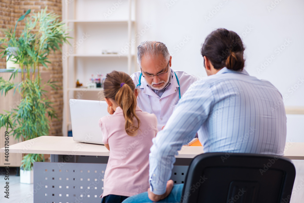 Obraz premium Small girl with her father visiting old male doctor