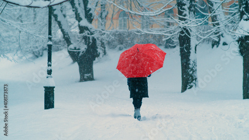 Young female goes for a stroll around the snowy park during covid-19 pandemic.