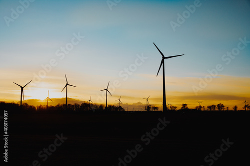 Wind turbines in the field. Wind farm at sunset. Blurred, black silhouette of a wind turbine. Wind energy in Germany