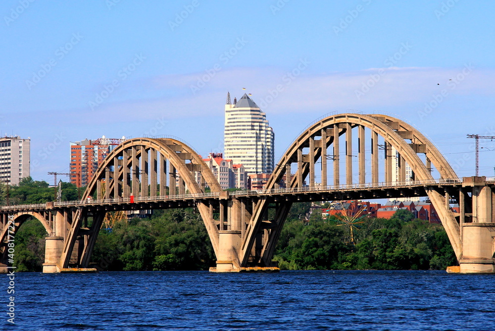Arched railway bridge over the river, skyscrapers, towers. Spring, summer view of the Dnipro river and the city Dnepropetrovsk, Dnepr, Ukraine.