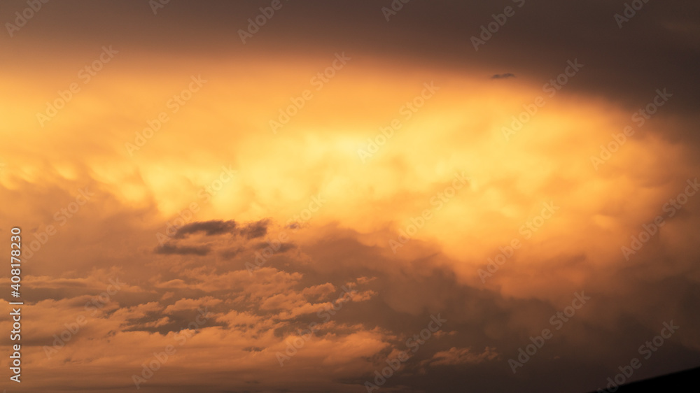Storm clouds at sunset glowing orange