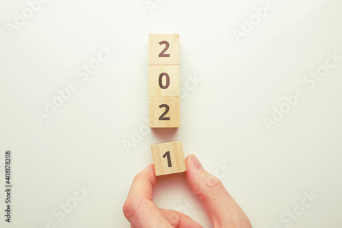 The concept of the transition to the new year 2021. Hand holds a wooden block.