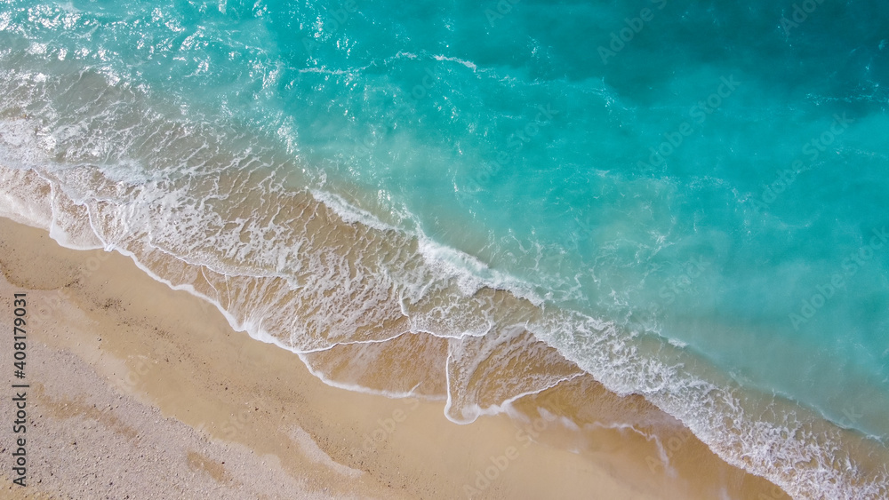 美しいアクアブルーの海と砂浜に白波が立つドローン俯瞰写真