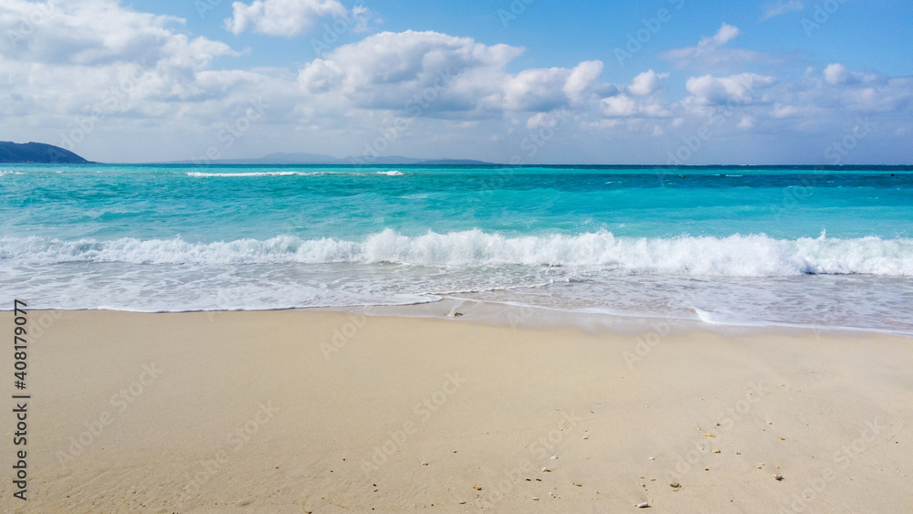 アクアブルーの海に白い波しぶきが映えるビーチの写真