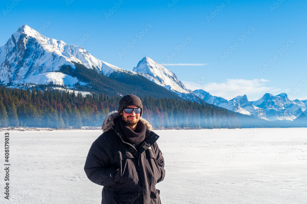 Maligne Lake, Canada - december 2020 : young man standing on the frozen lake in winter