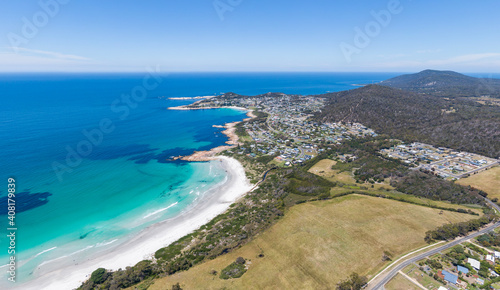 Stunning high angle aerial drone view of Bicheno, a beach resort town on the east coast of Tasmania, Australia on a sunny day. Redbill Beach in the foreground, Waubs Bay behind. Drone facing southeast