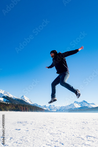 Young man jumping in the air at Maligne Lake, Canada