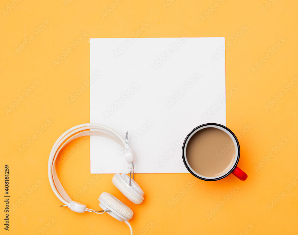 White mockup board and cup of coffee with headphones on yellow background White mockup board and cup of coffee with headphones on yellow background