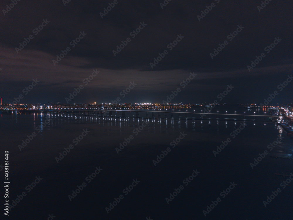 Fototapeta premium Drone view at night, with illuminated streets and dark sky. Beautiful cityscape
