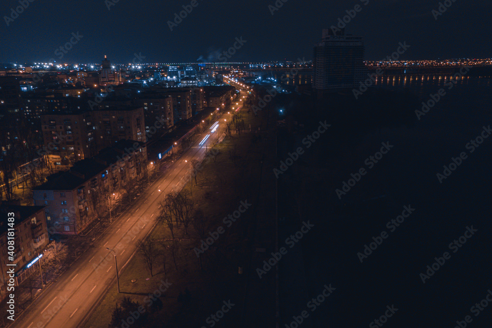 Drone view at night, with illuminated streets and dark sky. Beautiful cityscape