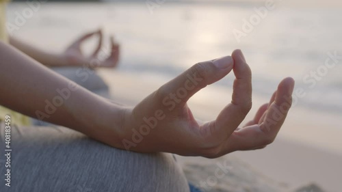 Hand of woman Practicing yoga on a beach in summer sunrise or sunset outdoor. Concept of relaxation and meditation