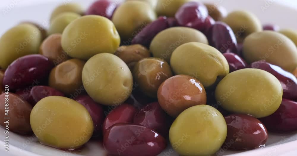 Olives in olive oil spin around themselves on white background. Rotating shot. Mediterranean organic fresh healthy food ingredient, slow motion, close up, macro Olives in olive oil spin around themselves on white background. Rotating shot. Mediterranean organic fresh healthy food ingredient, slow motion, close up, macro