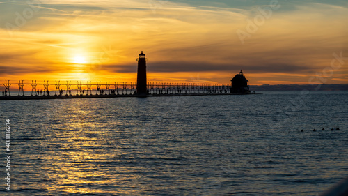 Grand Haven Lighthouse Michigan on Lake Michigan at sunset during the winter with beautiful colors and the structures and people silhouetted. Hot from North Pier.