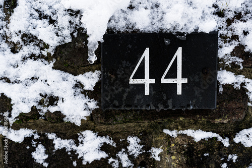 Number 44 in a covered with snow brick wall photo