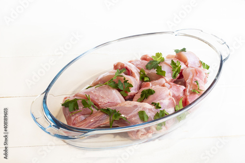 Closeup of the raw chopped chicken meat with cilantro leaf in a glass container photo