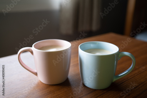 Pink mug and blue mug with cappuccino