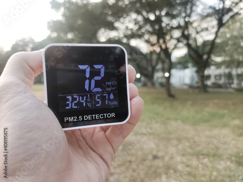 bad outdoor air quality. handheld pm2.5 dust sensor indicated harmful level of tiny dust particulate matter in the air. bad air quality even in park with lots of big trees.