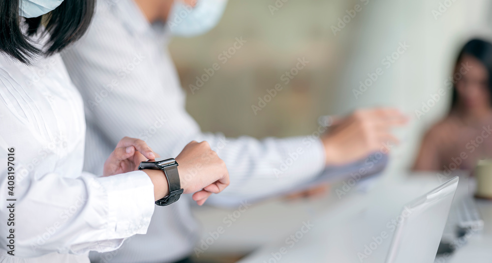 Cropped shot of female hands using smartwatch while working at office. Cropped shot of female hands using smartwatch while working at office.