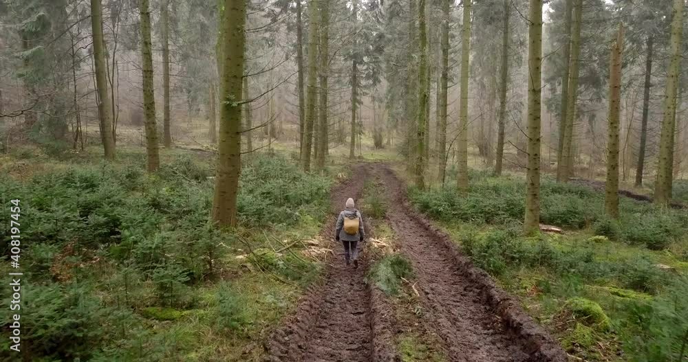 Following a young female with backpack walking through trees in the UK Following a young female with backpack walking through trees in the UK