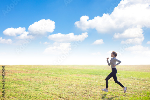 Young slim sports woman running on grass field