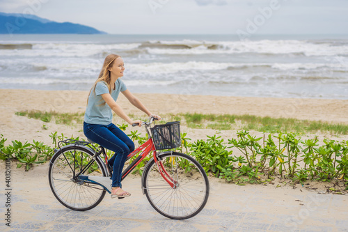Young woman with bicycle enjoying a bike ride by the sea © galitskaya