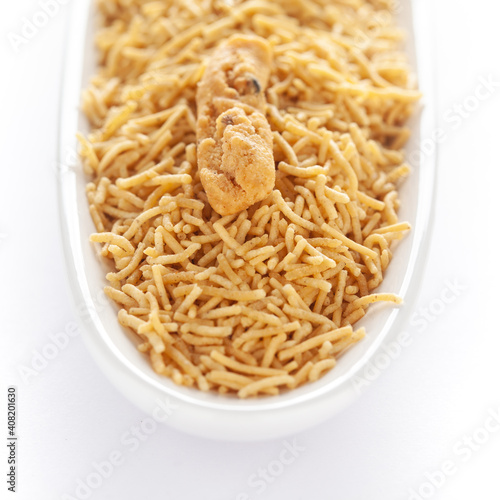 Indian spicy snacks (Namkeen) - Bikaneri Besan Bhujia in a white oval-shaped plate, made with chickpea flour (Besan), side view, against the white background.