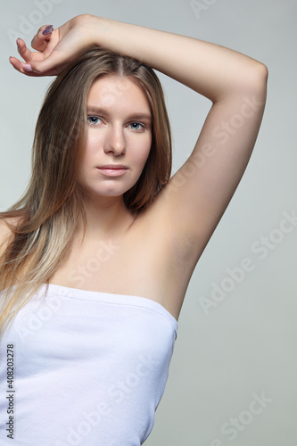 Portrait of young blonde woman with hand up.