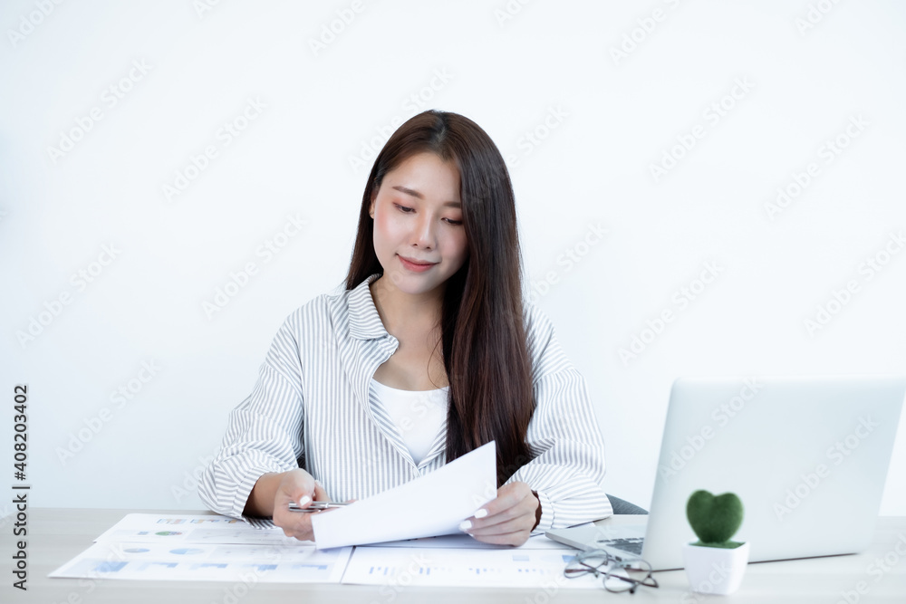 Asian female accountant sits at their desks and calculates financial graphs showing results about their investments, plan a successful business growth process Asian female accountant sits at their desks and calculates financial graphs showing results about their investments, plan a successful business growth process