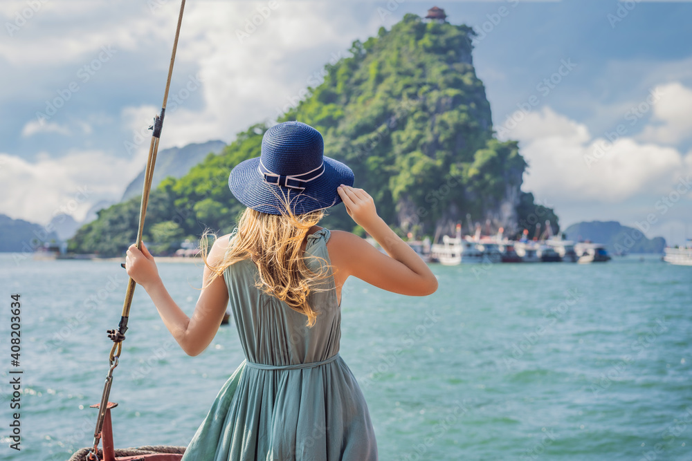 Attractive woman in a dress is traveling by boat in Halong Bay. Vietnam. Travel to Asia, happiness emotion, summer holiday concept. Picturesque sea landscape. Ha Long Bay, Vietnam