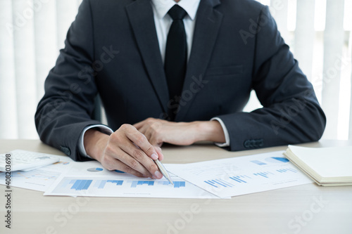 Fototapeta Naklejka Na Ścianę i Meble -  The businessman hand sits at their desks and calculates financial graphs showing the results of their investments planning the process of successful business growth