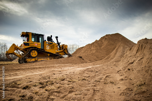 A yellow bulldozer pushes a full load of material into a pile.