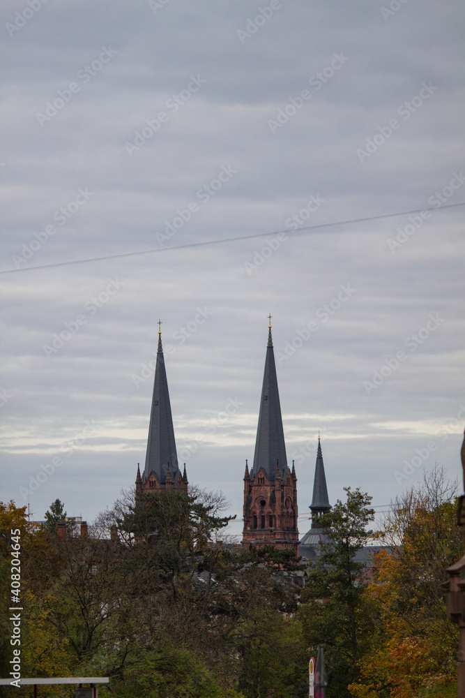 Fototapeta premium Freiburg im Breisgau, Germany - 11 01 2012: The spires of the Church against the grey sky. Empty european street on the cloudy autumn day
