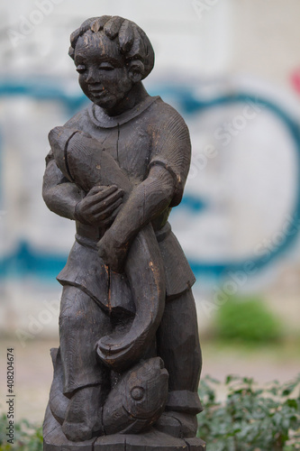 Freiburg im Breisgau, Germany - 11 01 2012: wooden statue of a boy with a fish in the park outdoors