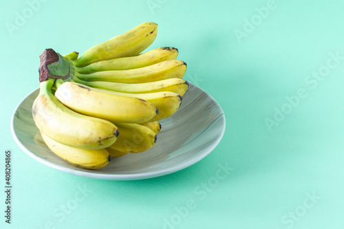 Ripe tasty banans on a plate on blue background. Healty eating concept photo