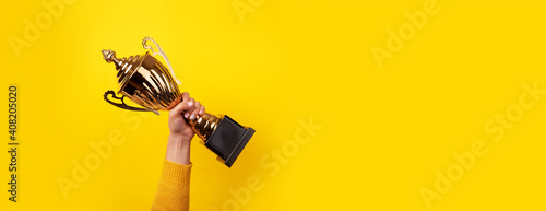 woman holding up a gold trophy cup as a winner in a competition, panoramic image photo